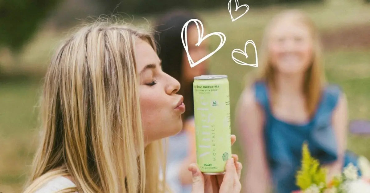 Woman playfully holding and kissing a non-alcoholic cocktail lime margarita Mingle can outdoors.