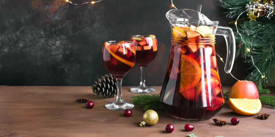 Sangria mocktail served in glasses with a holiday setup, featuring orange slices and cranberries