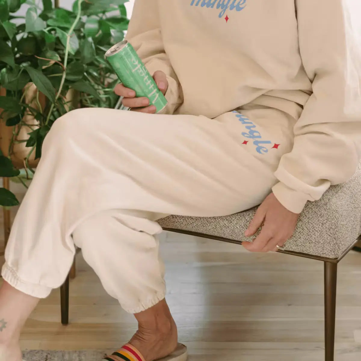 Cucumber melon mojito mocktail can held by a person in Mingle loungewear seated indoors on a modern chair.
