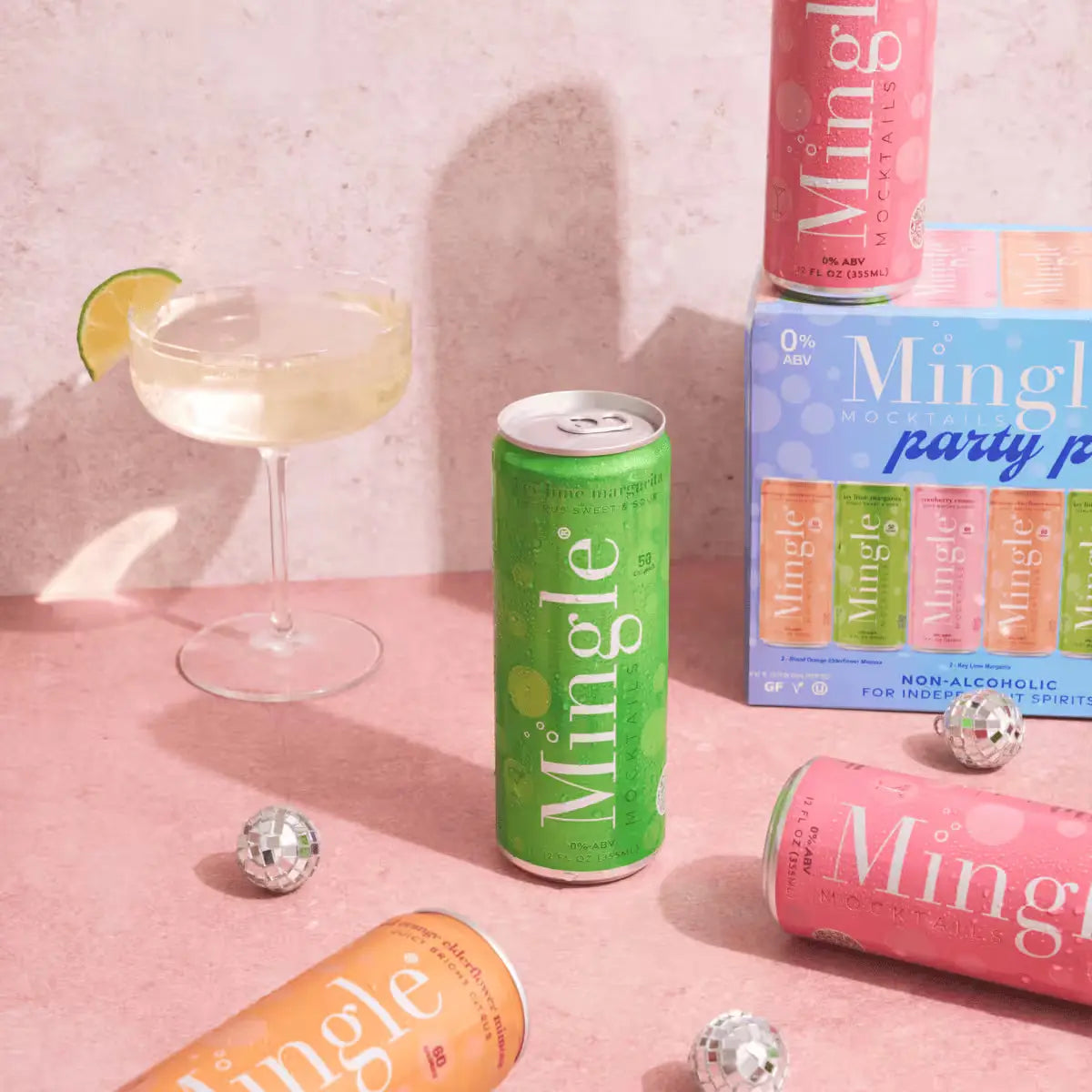 Ready-to-drink canned mocktails from Mingle displayed with party pack box, cocktail glass, and mini disco balls.