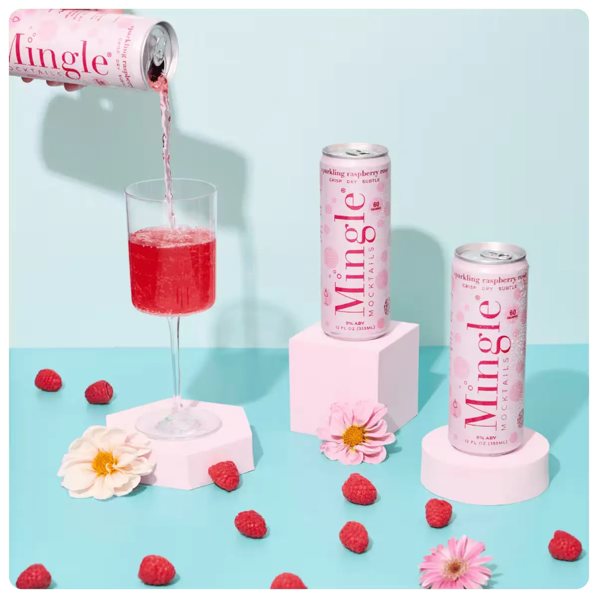 Sparkling raspberry rosé mocktails in pink Mingle cans with one being poured into a glass surrounded by raspberries and flowers.