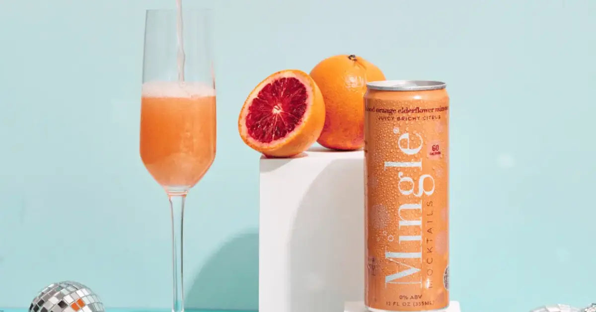 Blood orange mocktail presented in a can with fresh oranges and a champagne flute