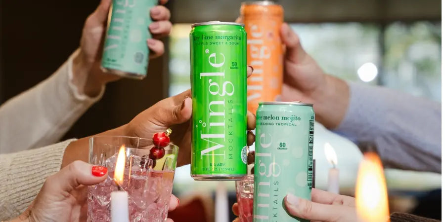Vegan mocktails in colorful Mingle cans raised in a celebratory toast, surrounded by candles and a festive atmosphere