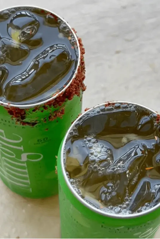 Spicy Pineapple Margarita mocktails made with Mingle Key Lime Margarita, served in open cans with a chili-rimmed edge