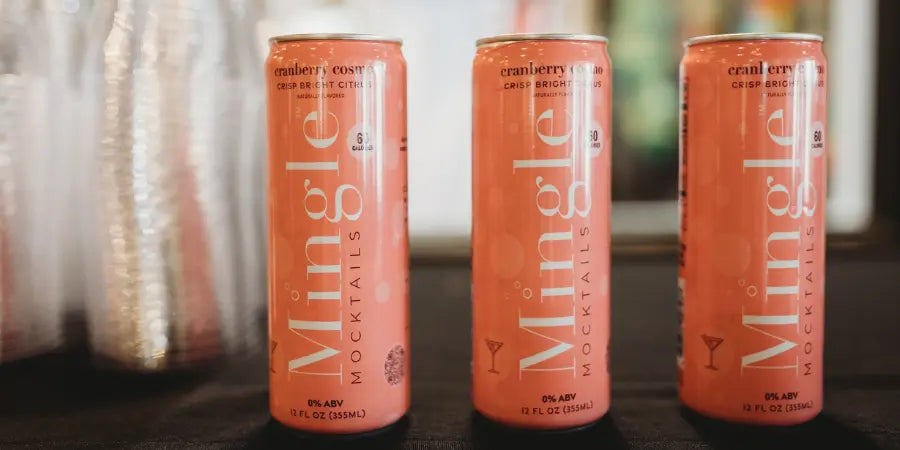 Three cans of Mingle Mocktails Cranberry Cosmo displayed on a table, offering a delicious alcohol-free mocktail option
