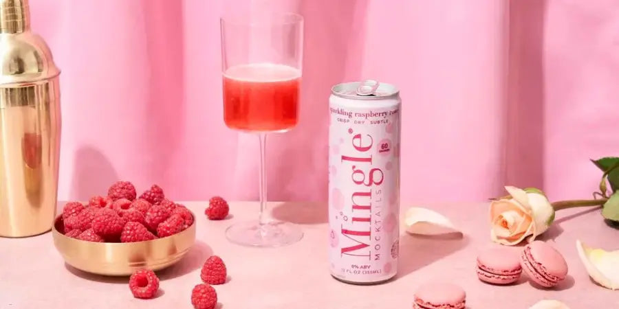 Mocktails for parties featuring sparkling raspberry rose cans and glasses with fresh raspberries on a pink table.