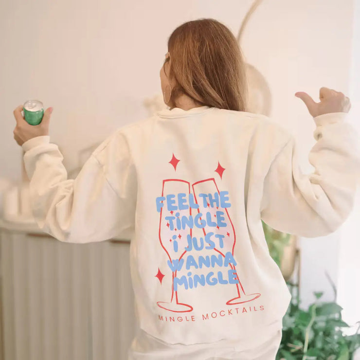 Woman wearing a sweatshirt with "Feel the Tingle, I Just Wanna Mingle" text and holding a can of Mingle Margarita mocktail