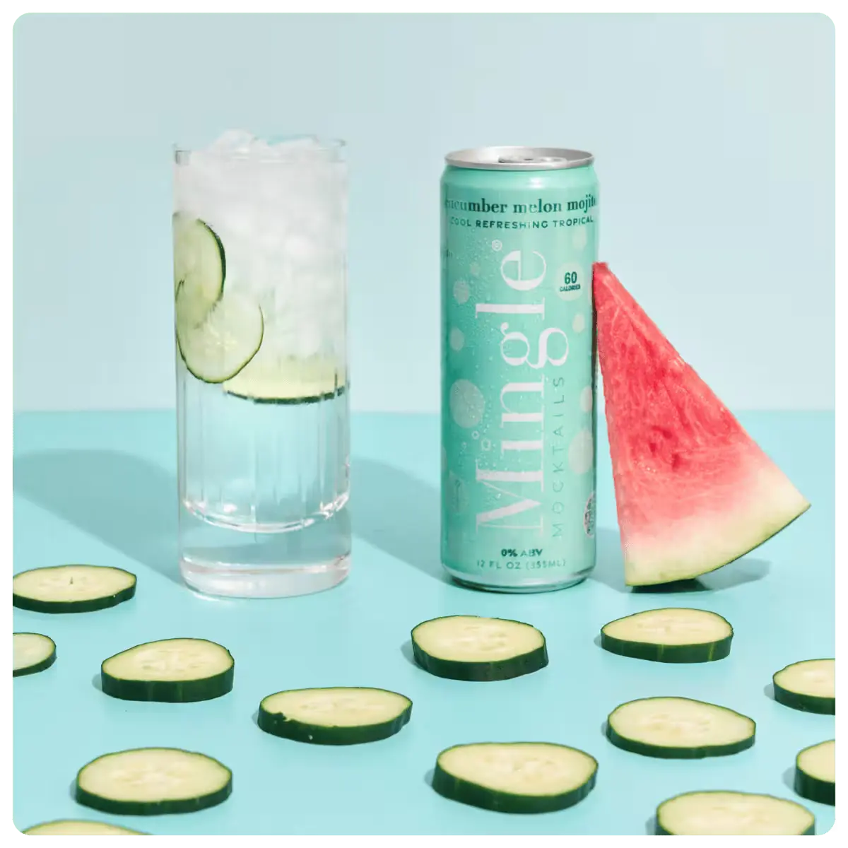 cucumber mojito mocktail can with a garnished glass, cucumber slices, and a watermelon wedge on a blue background