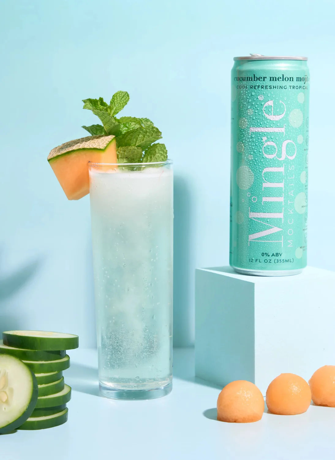 Mingle Mocktails Cucumber Melon Mojito turquoise can beside a tall glass garnished with melon, cucumber, and fresh mint.