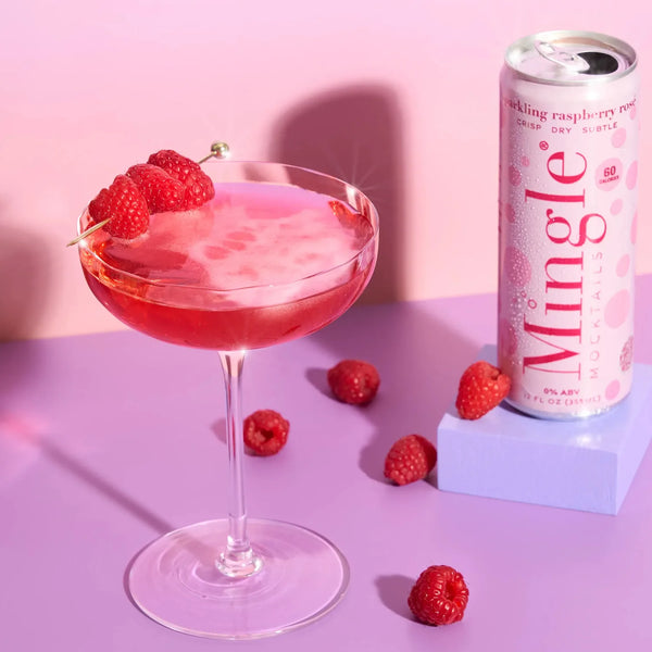 Mingle Mocktails Sparkling Raspberry Rosé served in a coupe glass with raspberry garnish beside the can on a lavender surface.